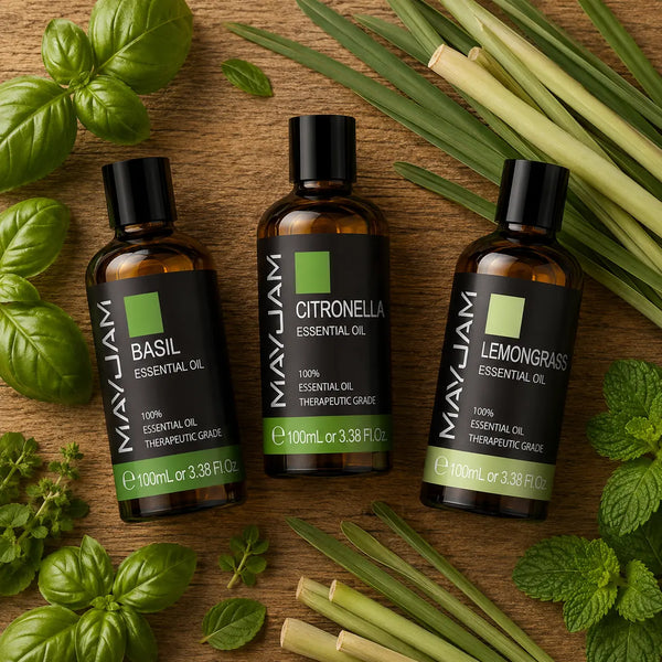 Három 100 ml-es  illóolaj (citromfű, citronella és bazsalikom) rusztikus fa asztalon felülnézetből, friss zöld növényekkel és gyógynövényekkel körülvéve.