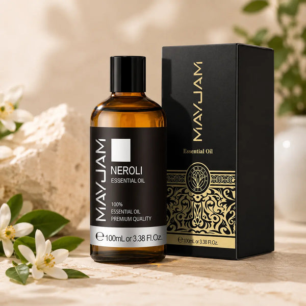 Neroli illóolaj 100 ml elegáns díszdobozban, borostyánszínű üvegben, fehér narancsvirágokkal díszített, világos természetes háttér előtt.